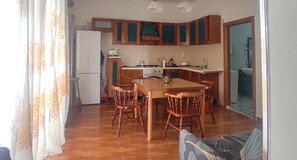 Una cocina con armarios de madera, una mesa de comedor con sillas y un refrigerador.