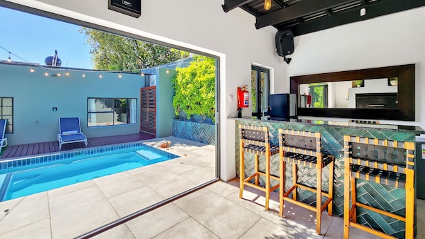 Un espace piscine extérieur moderne, doté d’un bar et de coins salon.