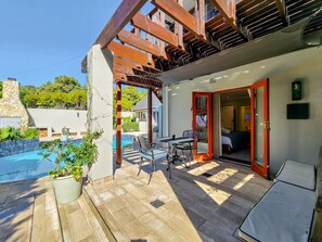 Un espacio exterior techado con piscina, muebles de patio y entrada a un edificio.