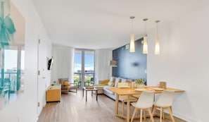 A modern living room with a dining area, large windows, and a view of the city.