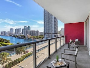 A balcony with a city view, a red wall, and a table with a tray of items.