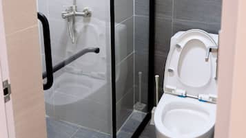 Et moderne badeværelse med bruseniche i glas, toilet og håndklædestang.