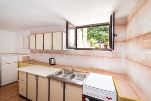 A kitchen with a window, a sink, a stove, and cabinets.