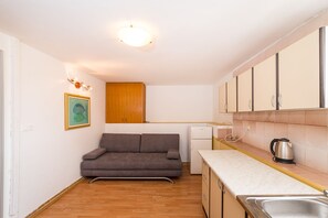 A compact kitchen with a sofa, a small refrigerator, and a kettle on the countertop. - Apartment Ljubica With Nice Garden 2 (Novalja)