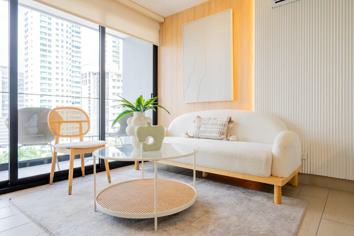 Una sala de estar moderna con un sofá blanco, una mesa redonda y una silla de mimbre.