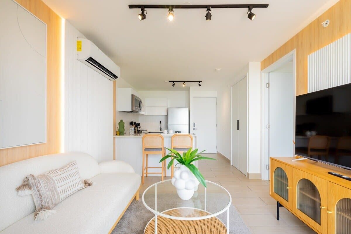 A modern living room with a sofa, a round coffee table, and a TV on a wooden cabinet.