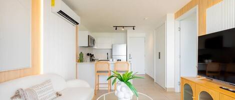 A modern living room with a sofa, a round coffee table, and a TV on a wooden cabinet.
