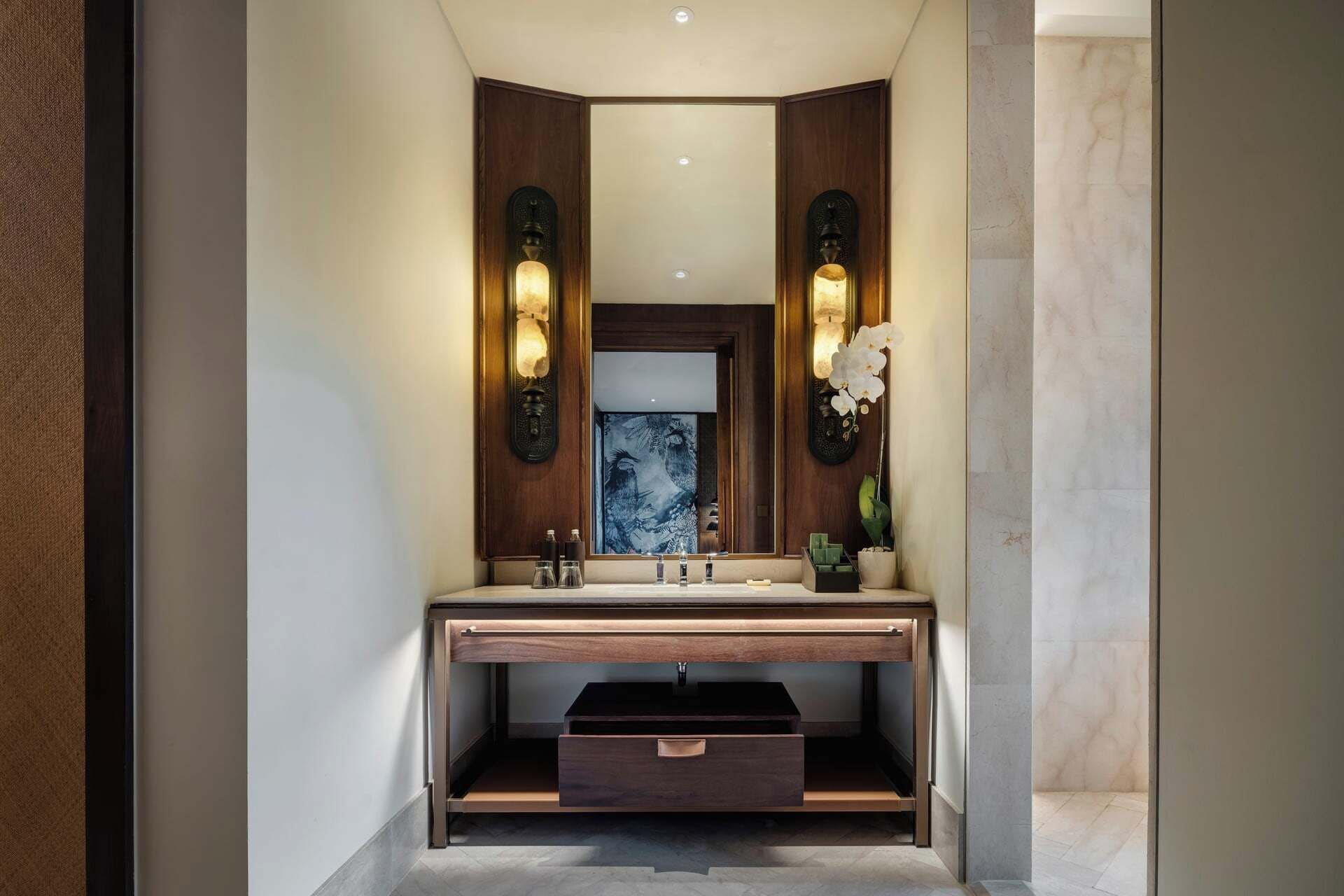 Une salle de bain moderne avec un meuble-lavabo en bois, un grand miroir et des appliques murales.