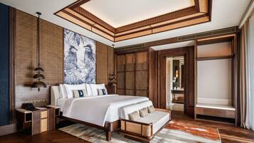 Una habitación de hotel moderna con una cama grande, cabecero de madera y vistas a una habitación de estilo asiático tradicional.