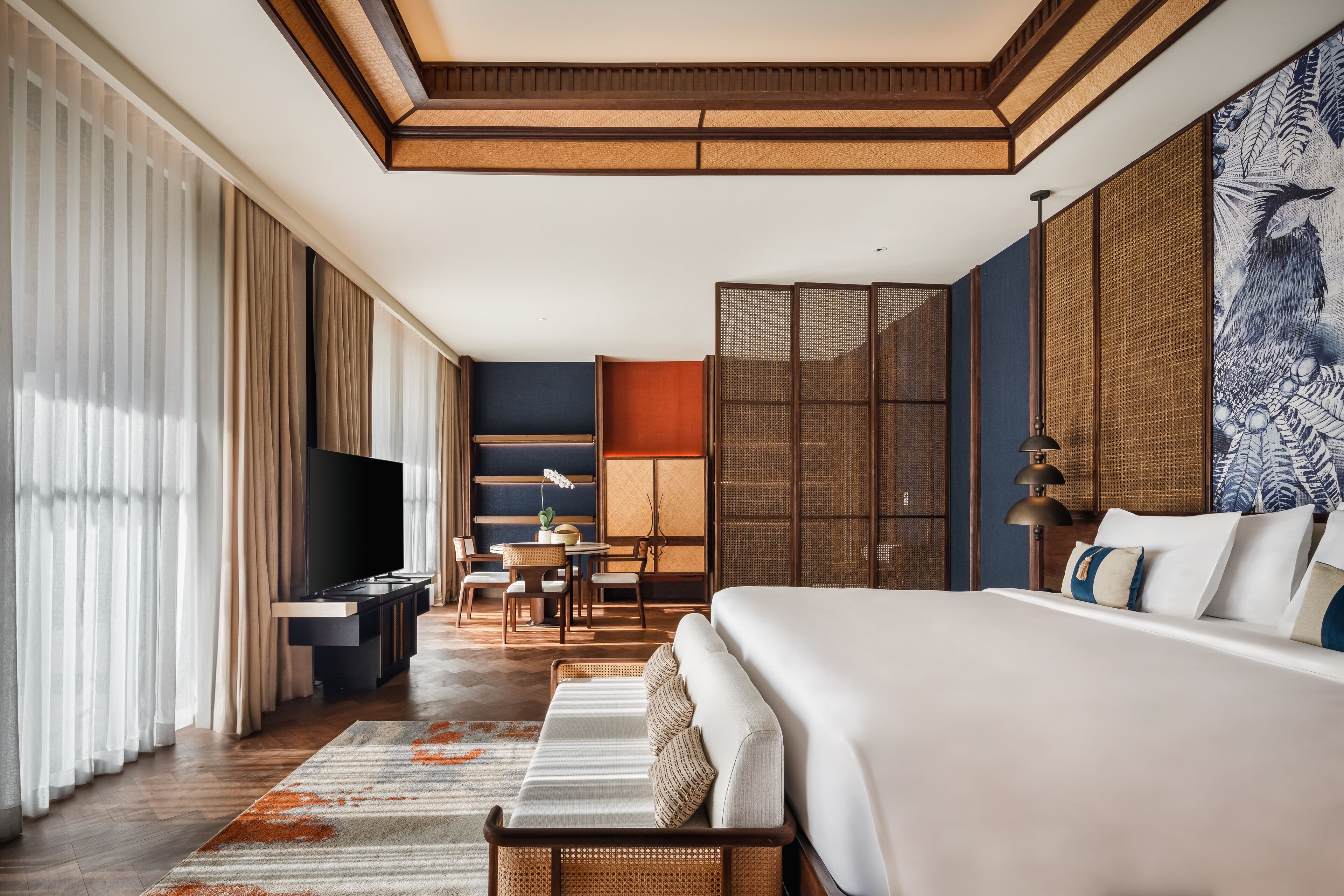 A hotel room with a large bed, a flat-screen TV, a dining area, and a view of the outdoors.