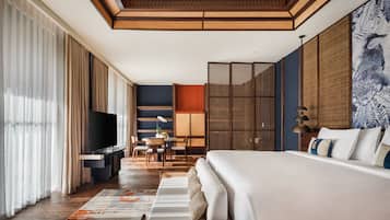 A hotel room with a large bed, a flat-screen TV, a dining area, and a view of the outdoors.