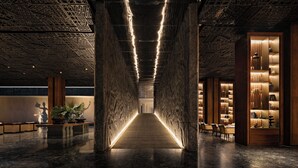 A modern interior with a central walkway flanked by wooden columns and illuminated by linear lights. - The Meru Sanur (Denpasar)