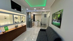En modern hotellobby med en receptionsdisk, en svart soffa, en matplats och en stor väggmålning med naturmotiv.