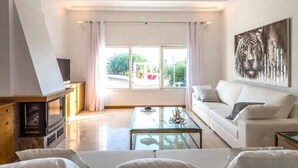 A modern living room with a sofa, coffee table, and artwork on the wall. - Beautiful  Villa Near ibiza Town and Talamanca Beach (Santa Eulària des Riu)