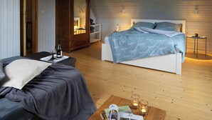 A bedroom with a bed, bedside tables, a wooden wardrobe, and a reading area with a table and chairs.