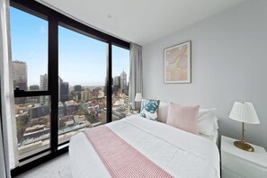 A hotel room with a large bed, a nightstand, a lamp, and a painting on the wall.