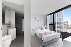 A modern bedroom with a bed, bedside table, and a large window with a city view.