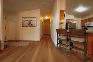 A hallway leading to a kitchen with wooden cabinets and a microwave. There are two chairs in the hallway. - Farmhouse - Peaceful 5 bedroom / 3 bath (Whitefish)