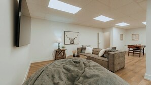 Een ruime kamer met een groot bed, een slaapbank, een salontafel en een bureau met een tafelvoetbal.