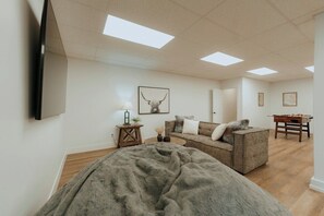 A spacious room with a large bed, a sofa, a coffee table, and a desk with a foosball table. - Farmhouse - Peaceful 5 bedroom / 3 bath (Whitefish)
