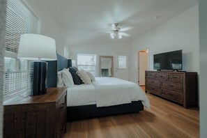 A bedroom with a bed, a dresser, a television, and a ceiling fan.