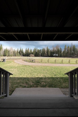 A covered outdoor area with a view of a fenced field and trees. - Farmhouse - Peaceful 5 bedroom / 3 bath (Whitefish)