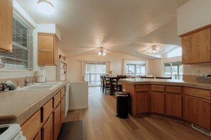 A spacious kitchen with wooden cabinets, a large island, and a dining area with a table and chairs. - Farmhouse - Peaceful 5 bedroom / 3 bath (Whitefish)