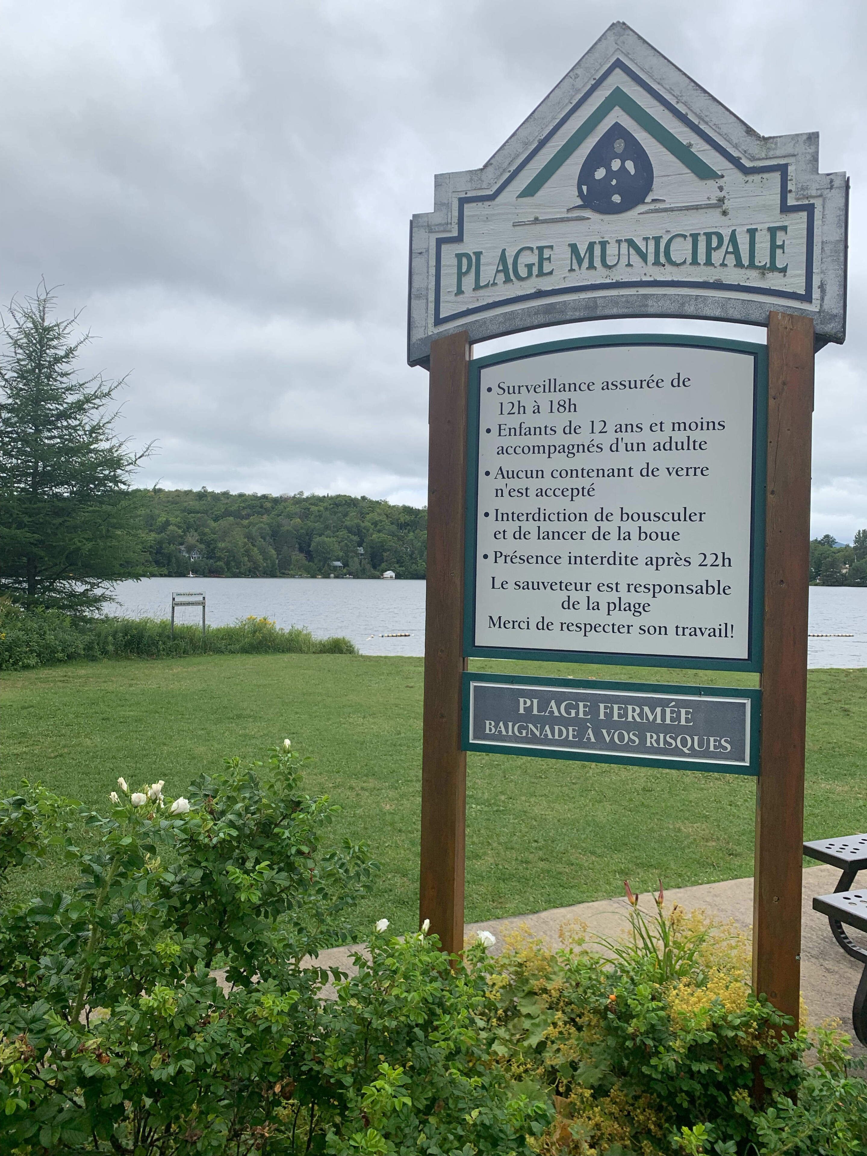 A sign for a municipal beach with rules and a warning about the beach being closed due to risks.