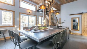 Una cocina moderna con una isla grande, vigas de madera e iluminación colgante.