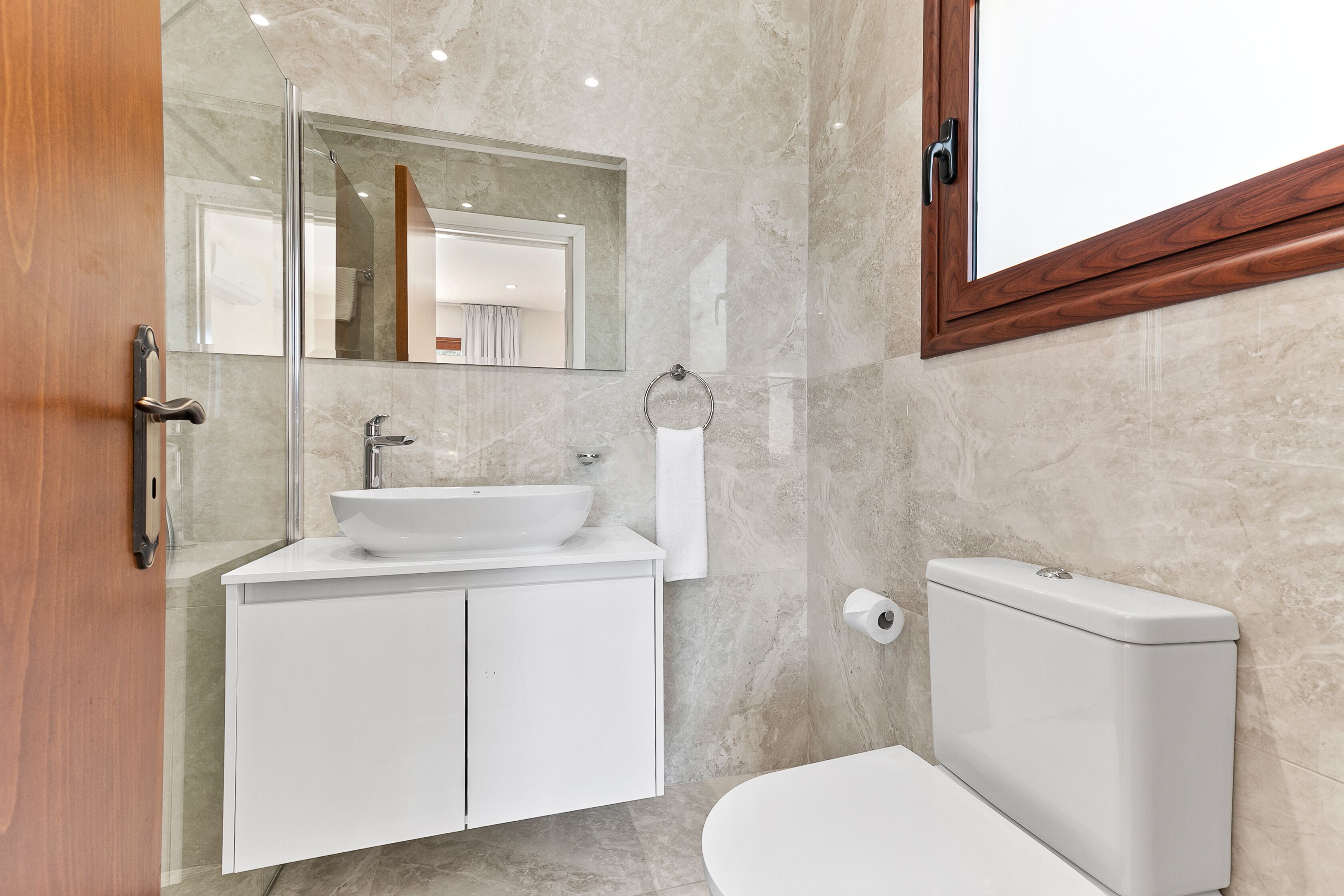 Ein modernes Badezimmer mit Waschbecken, Spiegel und Toilette in Weiß.