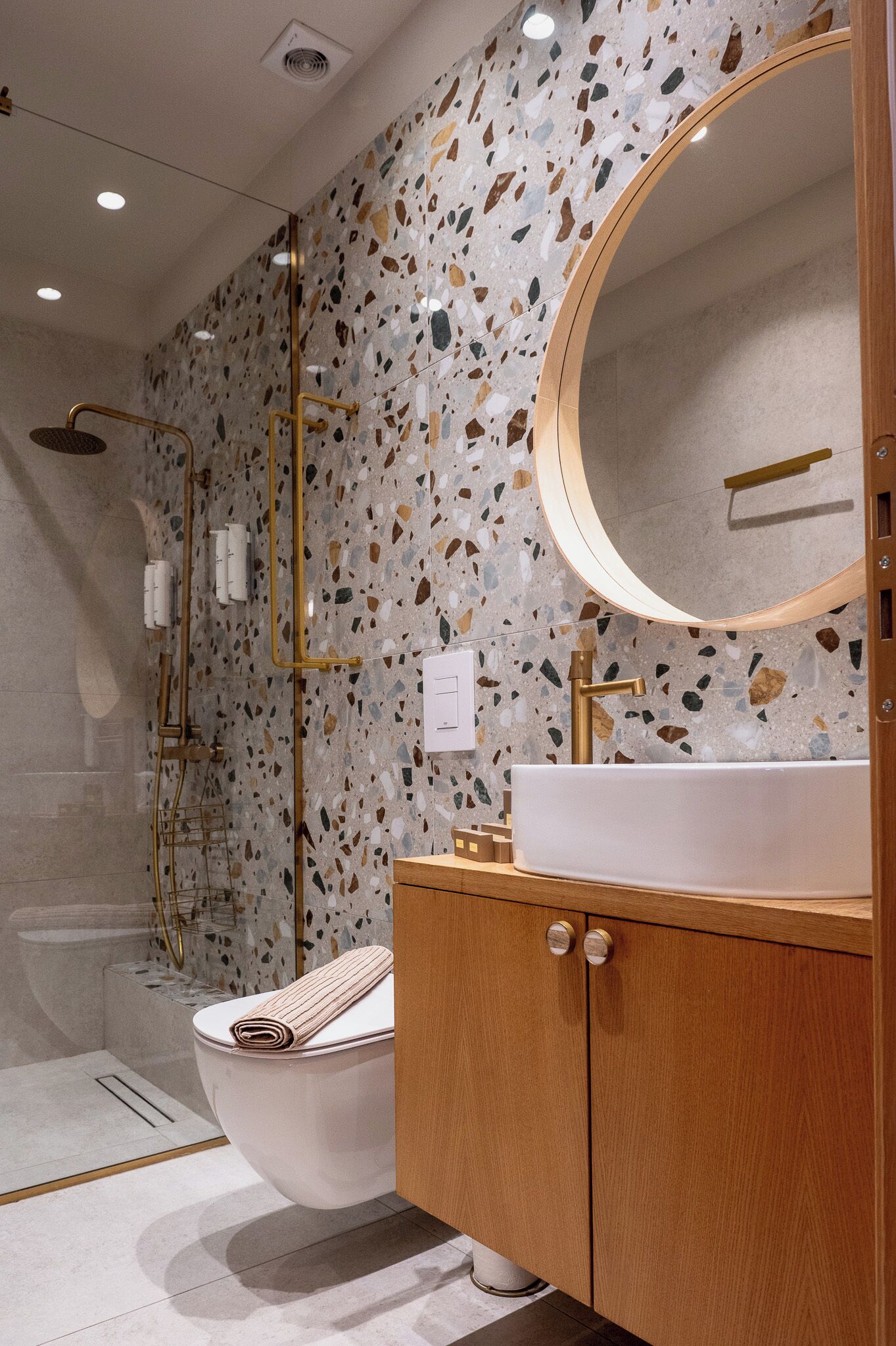 Une salle de bain moderne avec une baignoire sur pieds, un miroir rond et un meuble-lavabo en bois.