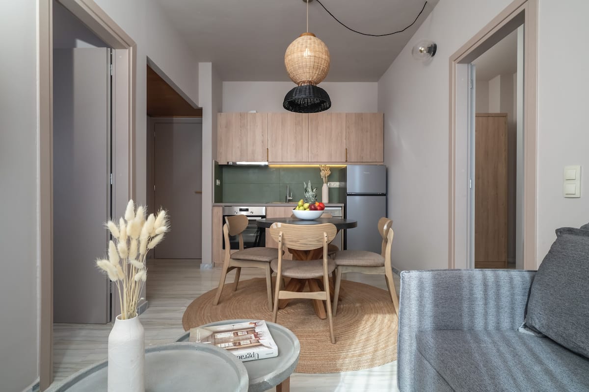 A compact living space with a kitchenette, a dining area with a round table and chairs, and a grey sofa.