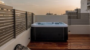 A rooftop terrace with a hot tub, wooden flooring, and a patterned cushion. - Num Suites & Lofts Athens (Athens)