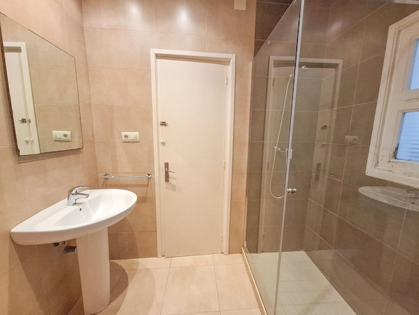 Ein Badezimmer mit Waschbecken, einer Tür und einer Duschkabine.