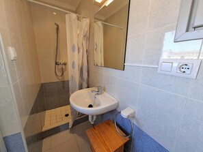 A bathroom with a shower, a sink, a mirror, and a towel rack.