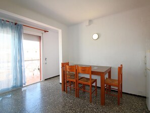 A dining area with a table and four chairs, a door with a curtain, and a wall-mounted light fixture.