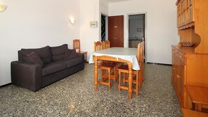 Un saló amb un sofà, taula de dinar, cadires i un armari de fusta.