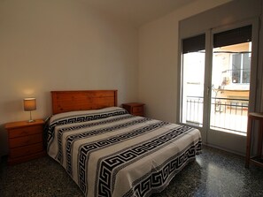 A bedroom with a bed, a nightstand, a lamp, a window with a view of the outside, and a balcony. - Bright Apartment Near Puerto Beach, 2 Double Beds, 1 Single Bed, Newly Renovated, WiFi (Llançà)