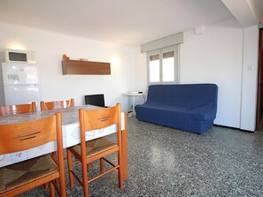 A compact living space with a dining table, chairs, a sofa, a small table, and a microwave. - Penthouse avec Grande Terrasse, à 100 m de la Plage de Llançà, Rénové, avec WIFI en Été (Llançà)