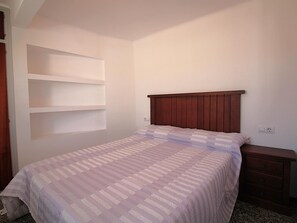 A bedroom with a bed, a wooden headboard, a nightstand, and built-in shelving. - Penthouse avec Grande Terrasse, à 100 m de la Plage de Llançà, Rénové, avec WIFI en Été (Llançà)