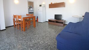 A compact living space with a kitchenette, a dining area, a television, and a sofa. - Penthouse avec Grande Terrasse, à 100 m de la Plage de Llançà, Rénové, avec WIFI en Été (Llançà)