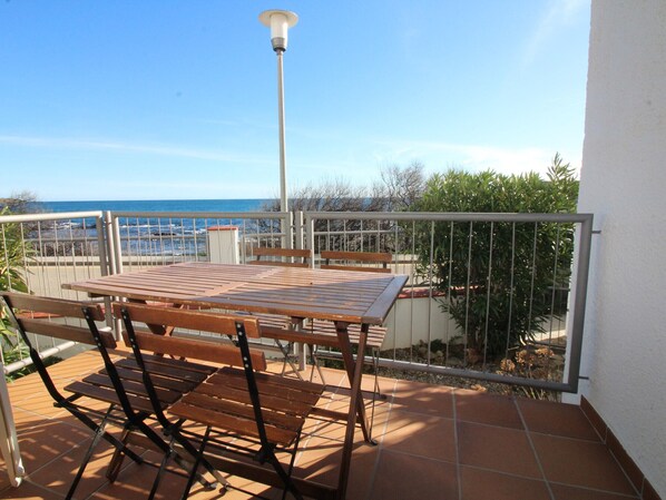 A balcony with a table and chairs, a lamp, and a view of the sea.