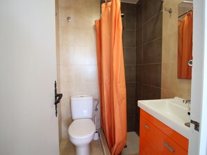 Une salle de bain avec des toilettes, un rideau de douche et un lavabo, le tout agrémenté de meubles orange.