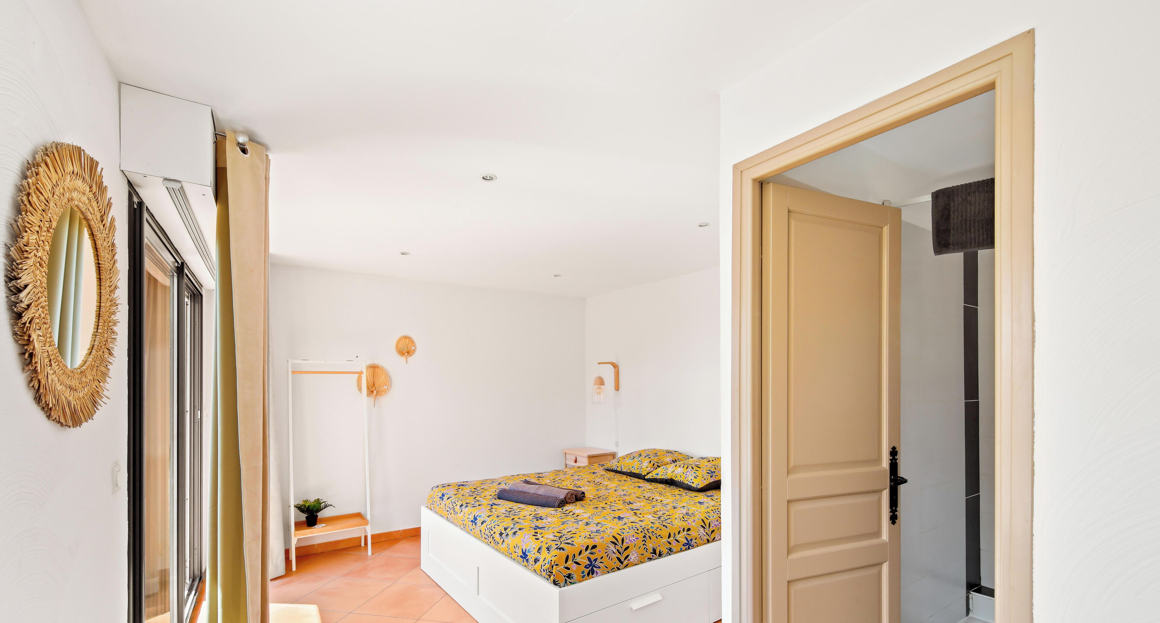 Une chambre à coucher avec un lit, un banc, une plante en pot et un miroir.