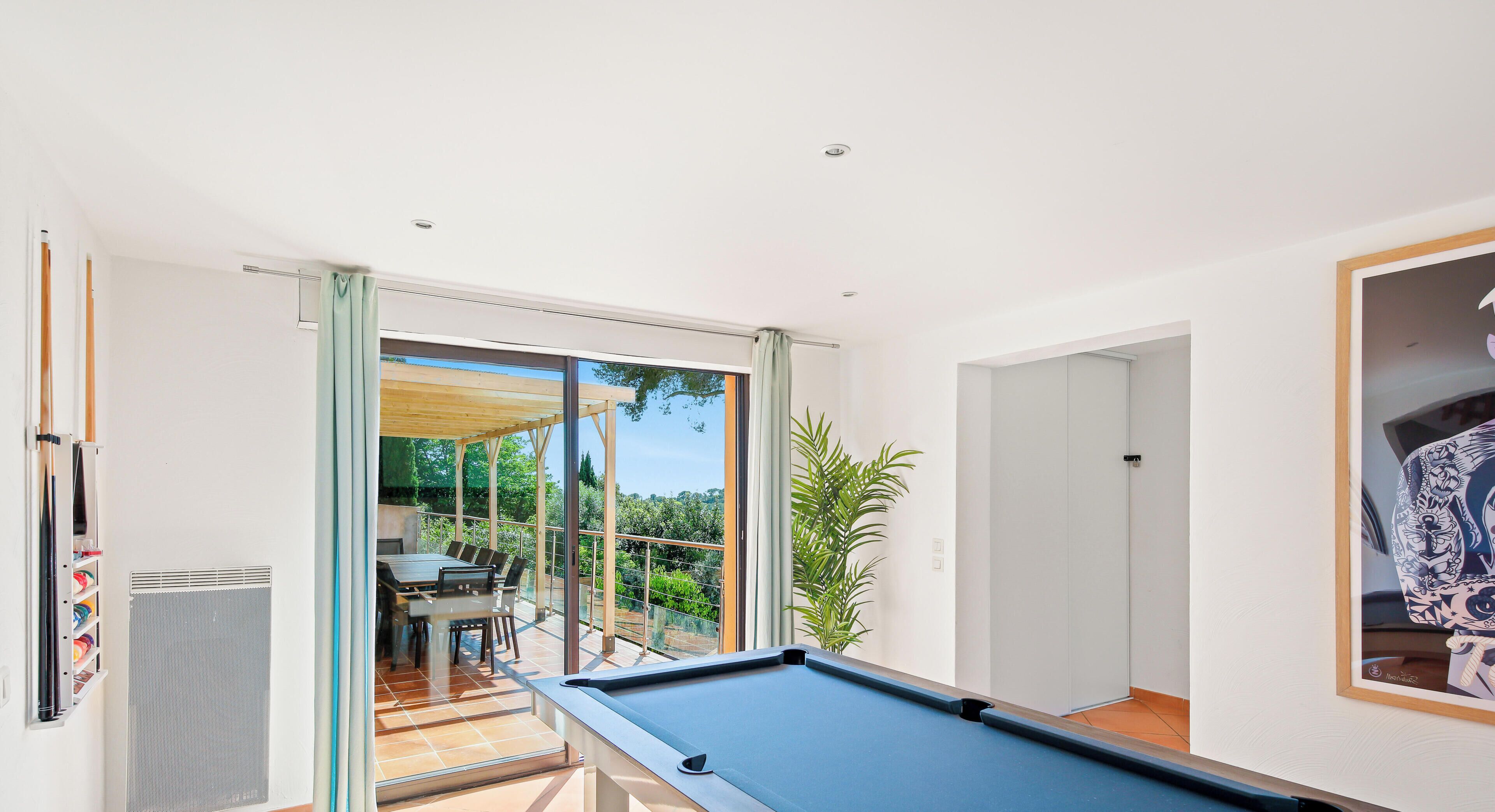 A pool table in a room with a view of a patio area.