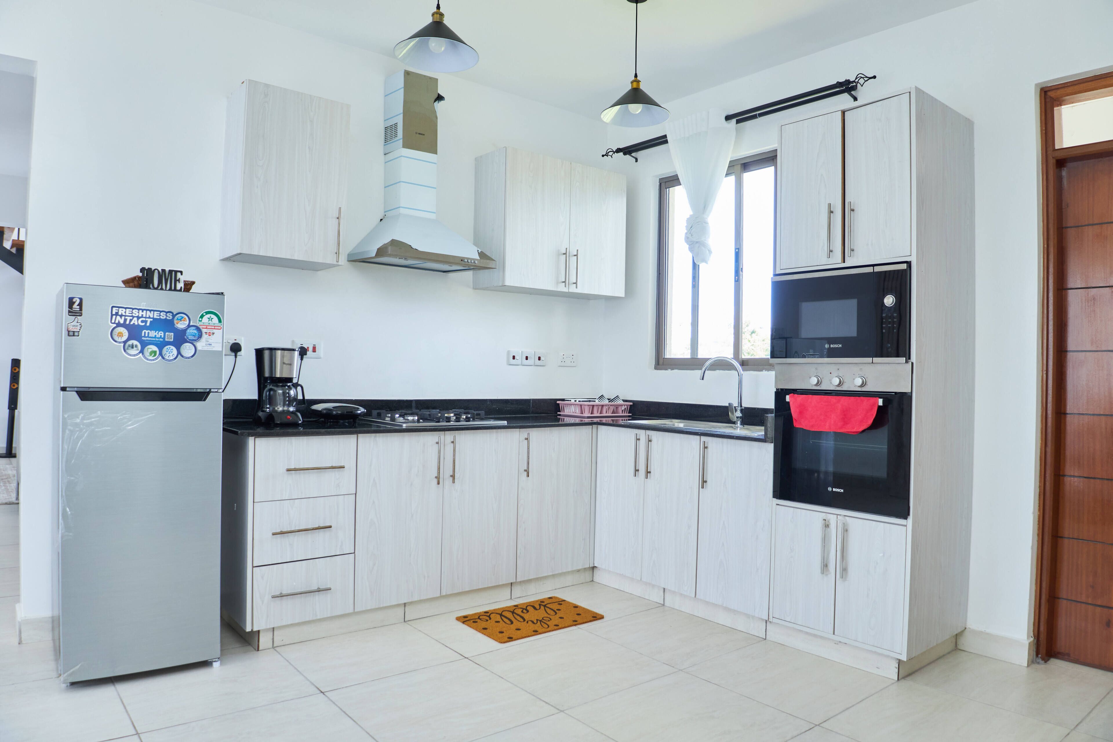 Una cocina moderna con armarios blancos, un microondas negro y un refrigerador de acero inoxidable.