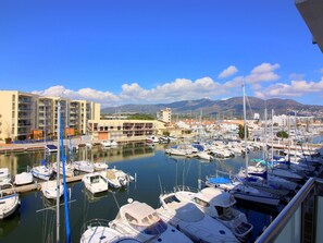 Boats fill the marina, surrounded by nearby buildings and majestic mountains.