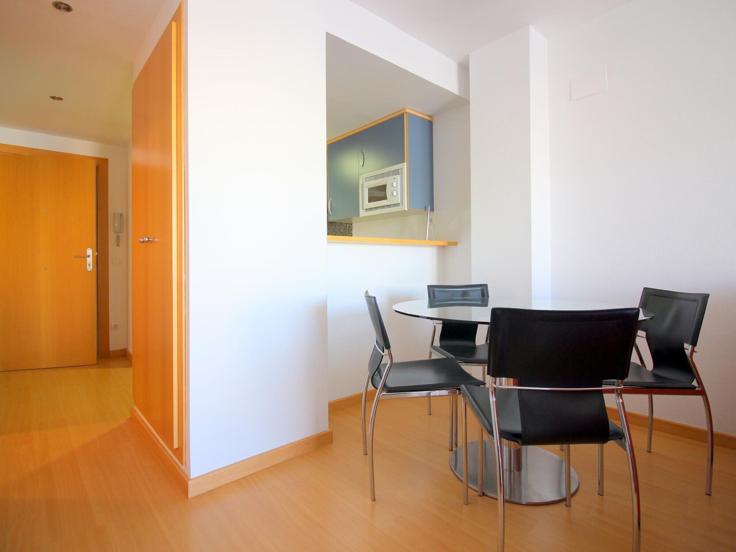 A modern dining area with a round table and four black chairs.