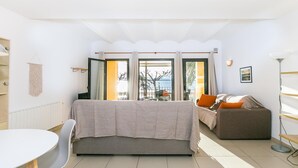 Una sala de estar moderna con un sofá, una mesa de comedor con sillas y vistas al mar a través de amplios ventanales.