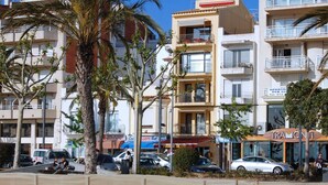 Un edificio de varios pisos con balcones, un restaurante llamado "TRAMONTI" en la planta baja y una zona arenosa al frente.